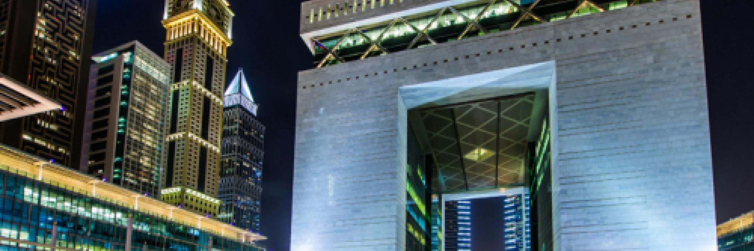 Picture of an arch lit up in Dubai with tall buildings in the background