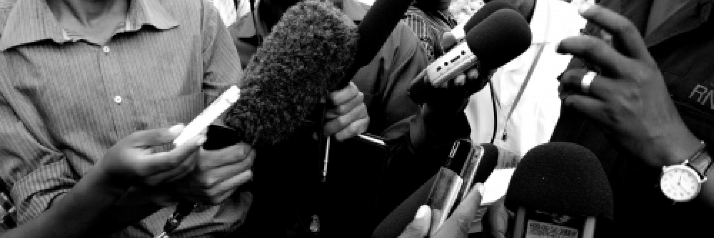 Photo of a group of journalists with microphones held in front of them