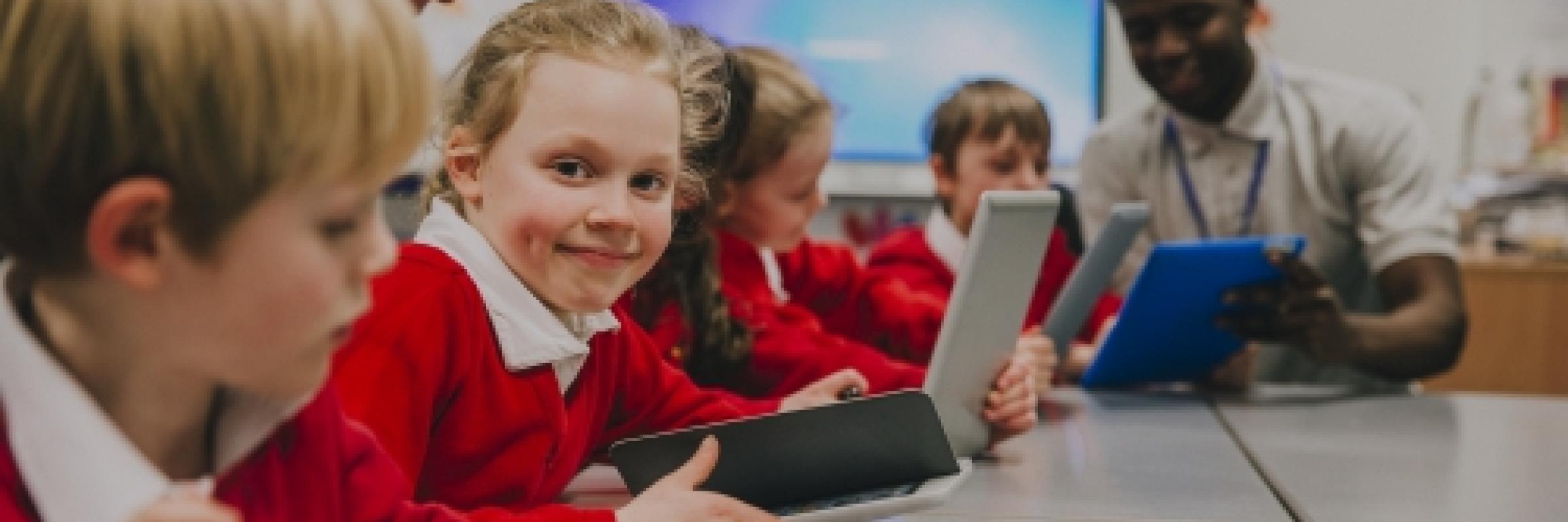 Primary school children working on laptops and tablets.