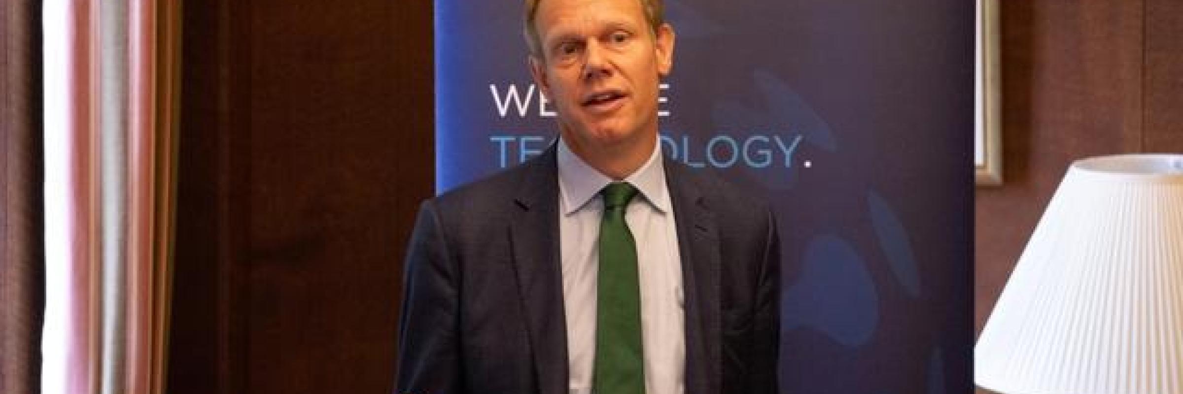 A man in front of a lectern addressing an audience