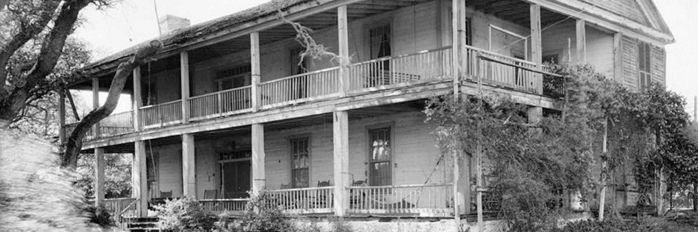 Black an white image of the front of a plantation house in Washington County, Texas, with a tree and grass in front of it