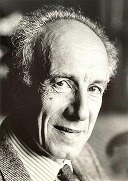 Side profile of a man wearing a suit and tie, smiling at the camera