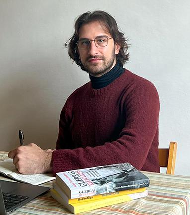 Person sat at a desk with a pen and books