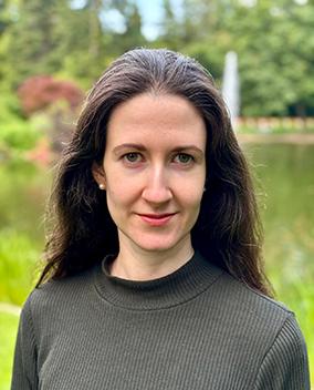 A person with long hair in front of a pond.