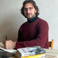 Person sat at a desk with a pen and books